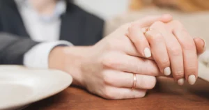 Manos de pareja casada con anillos de boda, simbolizando el vínculo matrimonial y la pregunta legal sobre quien hereda los bienes adquiridos antes del matrimonio.